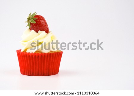 Red cupcake with white cream decorated with strawberry on white background. Picture for a menu or a confectionery catalog.
