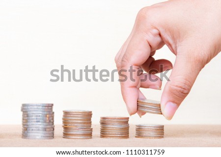 Saving money concept. Finger hold stack coins to arrangement with shown concept of growing business and wealthy. Royalty-Free Stock Photo #1110311759