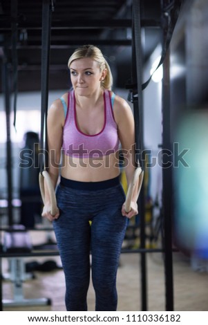 young athlete woman working out pull ups with gymnastic rings at the cross fitness gym