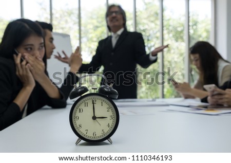 Clock show time,with senior manager bored with new generation of employees who not interested in meeting blur background.
