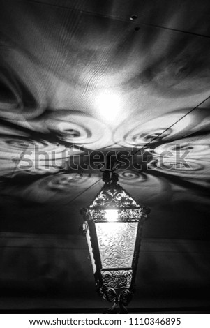 A beautiful old lantern gives beautiful shadows at night. Black and white photo.
