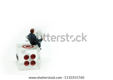 Miniature people, businessman sitting on dice. Picture use for business competition concept or business game concept.