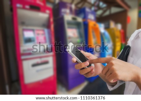 Girl use mobile phone, blur image at ATM machine as background.