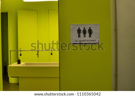 Toilet signage of all kinds next to a bathroom door in acid green with icons of the man, the woman, the transgender. Black icons on a white background.