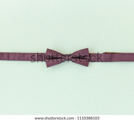 Crimson (dark red/almost purple) bow tie on light pastel blue flat lay