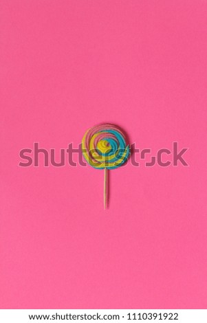Creative view of colorful, handmade swirl lollipop in summer colors on pink paper background. Minimalism. Abstraction. Creativity. Top view.