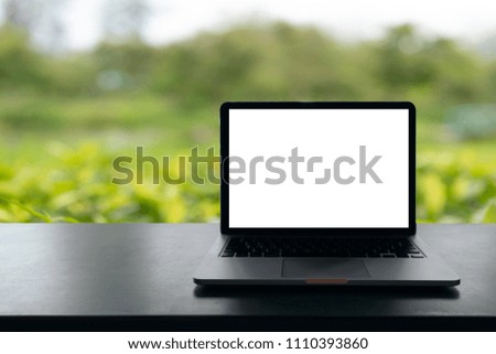 Laptop with blank screen on table, Conceptual workspace, Laptop computer with blank white screen on table, Green blurred background.
