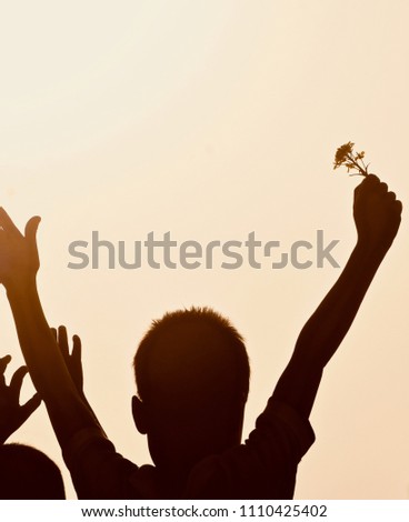 Silhouette young boy holding a flower raised his two hands up isolated unique photo