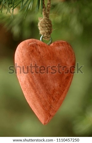 A red wooden heart and green background