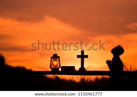 The boy sit and praying to God with oil lamp and cross, christian concept.