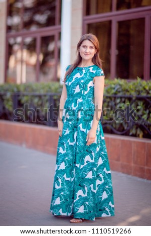 Young beautiful woman in a long green dress on the street