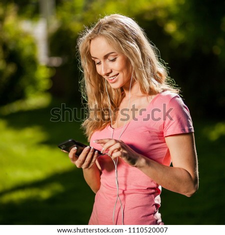 cheerful girl is typing a message on the phone in the Park
