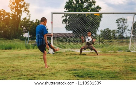 An action sport picture of a group of kid playing soccer football for exercise in community rural area under the sunset. 