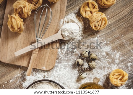 Raw homemade pasta and ingredients for pasta on a wooden background