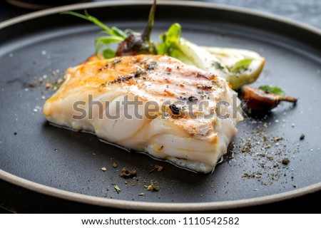Modern Thai fried cod fish filet with bok choi and mushrooms as close up on a plate 