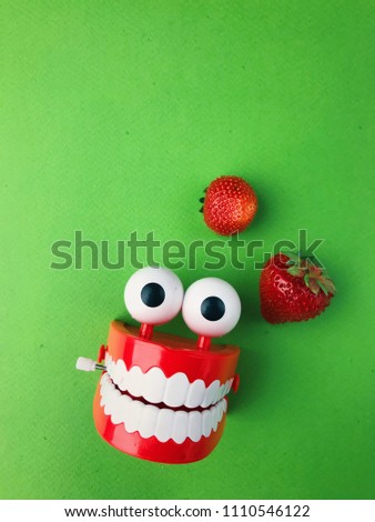 funny picture of teeth on a green background with red strawberries