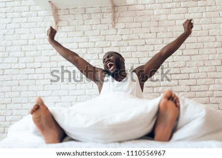 Happy awakened man is stretched out in bed. Early morning. Pleasant awakening. Waking up. Royalty-Free Stock Photo #1110556967