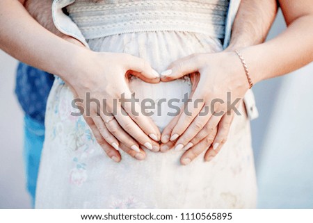 Cropped image of beautiful pregnant woman and her handsome husband hugging the tummy