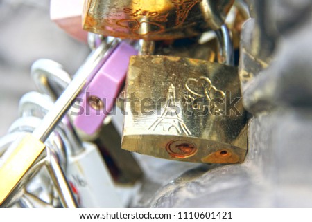 Padlock of love with the Eiffel tower and two enchained hearts engraved in a bridge of Paris, France