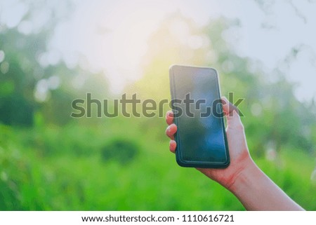 Copy space lady hand using smartphone with green nature abstract background.