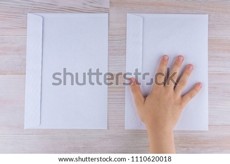 the boy makes a choice of two envelopes, laying his hand on the right, reduced contrast