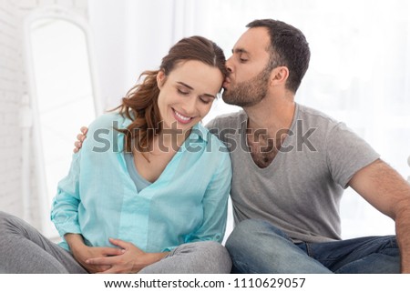 Mom and wife. Charming pregnant woman and man sitting and man kissing