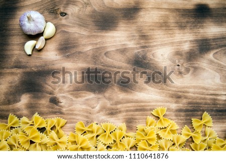 raw Farfalle lie at the bottom of the frame on a wooden table top view with free space at the top of the picture