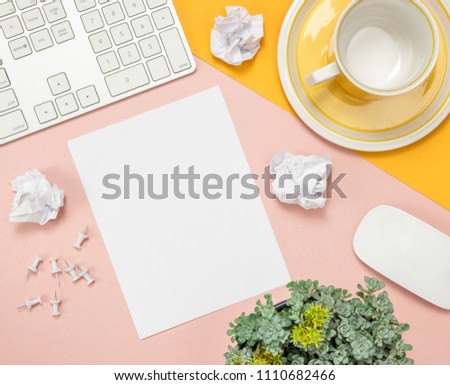 Bright summer home office workspace with blank sheet of paper in the middle. Flat lay composition on pink and yellow background.