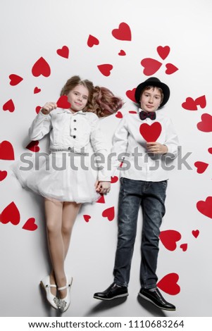 Happy pre-teen boy and girl  are posing surrounded by hearts. Friendship. First love. Valentine's Day. 