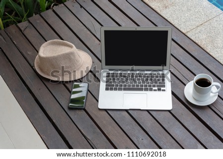 Laptop computer and smart phone with coffee cup  and hat on wooden. laptop or notebook and hat at the pool. 