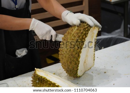 Chef's hands holding a Knife while peeling fresh durian                              