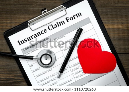Health insurance claim form for fill out. Empty form near heart sign and stethoscope on dark wooden background top view