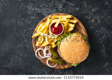 Burger, hamburger or cheeseburger served with french fries, pickles and onion on wooden board. Top view. Fast food concept