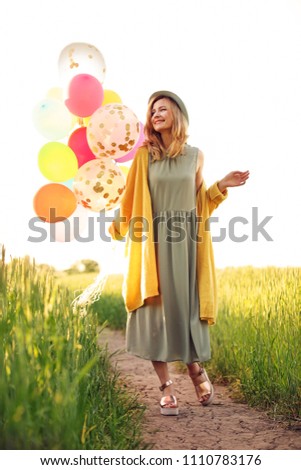 Young woman with colorful balloons outdoors on sunny day