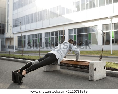 Guy playing sports in the city. Young athlete doing exercises on the bench. Warm up before morning training. The photo represents the sport and a healthy lifestyle.