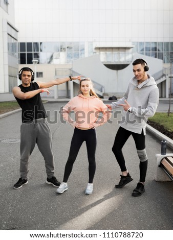 Three friends play sports in the city. Warm up before morning training. The photo represents the sport and a healthy lifestyle.