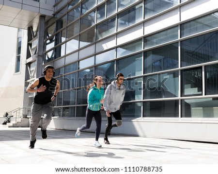 Three young athletes train in the morning in the city. Morning jog in the city. A ray of morning light hits the frame. The photo reveals a sports theme.