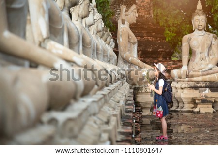 Asian girl tourist holding a lotus with respecting or pray at Wat Yai Chaimngkol, Ayutthaya,Thailand, summer vacation,travel concept.