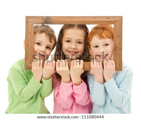 Three happy smiling kids looking through picture frame. Isolated on white.