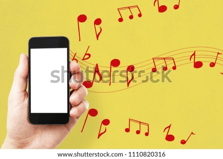 Male hand holding empty white mobile phone on yellow background with notes. Music, leisure, device and entertainment concept. Mock up 