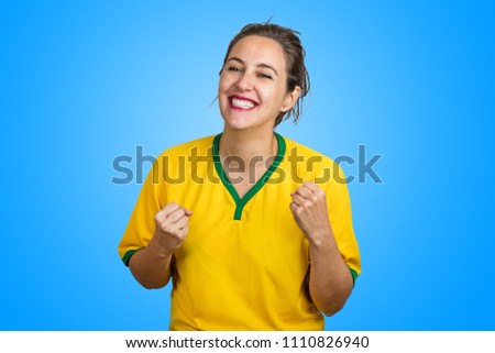 Brazilian female fan celebrating with beautiful smile on blue background. Woman cheering for Brazil in the cup.