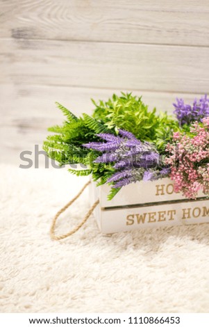 Flowers in a white wooden box. Interior decoration, interior composition. Flowers and branches in a wooden box on a white wooden background