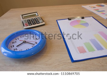 Clock, calculator, pen, graphics on table. Business graph pictures. financial concept