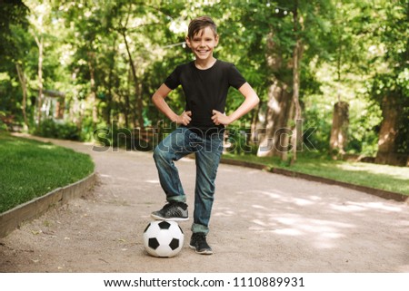 Picture of happy little boy outdoors in park nature play football looking camera.