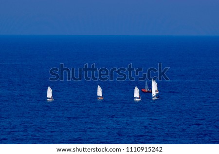 Racing sail boats in deep blue Mediterranean sea with clear sky at background. Greece, Kavala