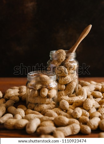 Pile of peanuts in glass jars and on wooden table