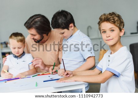 selective focus of father helping sons draw pictures with colorful pencils at home