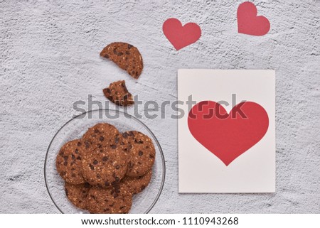 Homemade chocolate cookies on glass plate and heart shape paper card. Valentine's day concept.