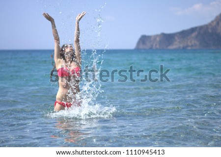 Girl with red bikini plays in the water