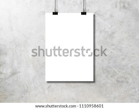 White paper or poster hanging by a clip on a concrete wall background.